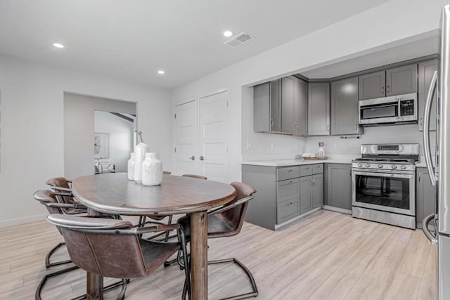 kitchen with gray cabinetry, light hardwood / wood-style floors, and appliances with stainless steel finishes