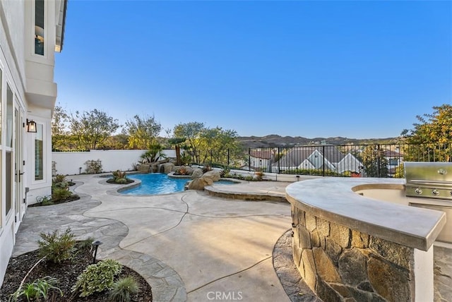 view of pool with a mountain view, a patio area, grilling area, and exterior kitchen