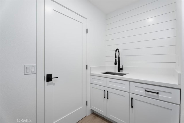 bar featuring white cabinetry, sink, and light hardwood / wood-style floors