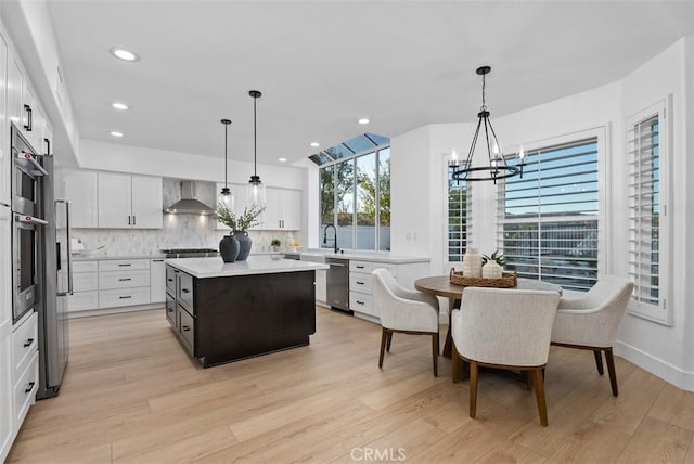 kitchen with pendant lighting, white cabinets, and wall chimney exhaust hood