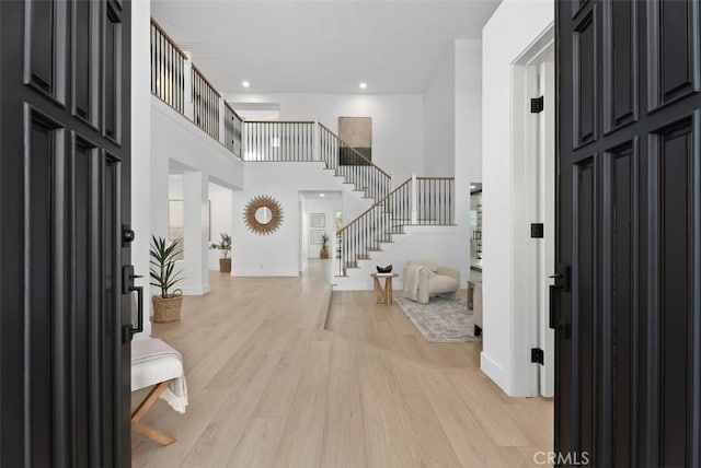 entryway with a towering ceiling and light wood-type flooring