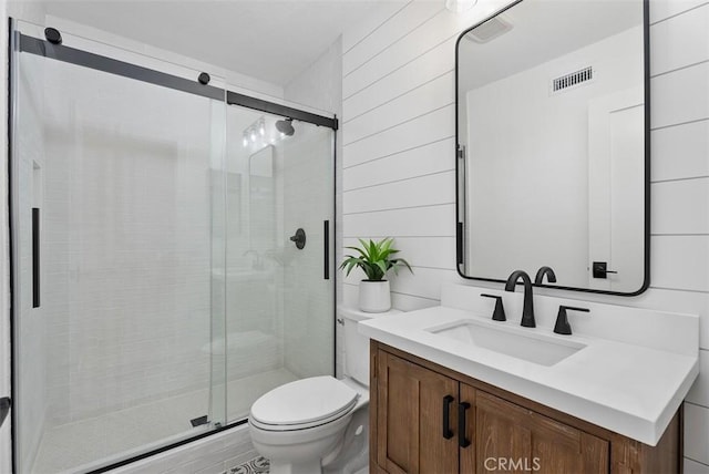 bathroom with vanity, walk in shower, wood walls, and toilet