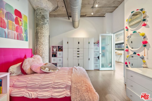 bedroom featuring hardwood / wood-style floors and a towering ceiling