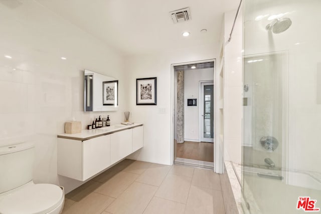 bathroom featuring a shower with door, vanity, tile patterned flooring, and toilet