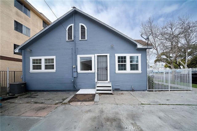 back of property featuring entry steps, fence, central AC unit, and a patio