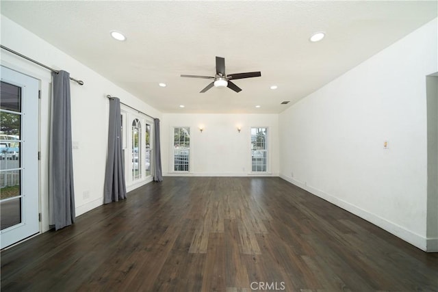 spare room featuring dark wood-type flooring, recessed lighting, plenty of natural light, and baseboards