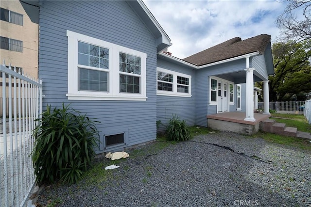 view of home's exterior with a porch and fence