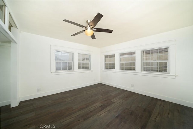 unfurnished room featuring baseboards, dark wood finished floors, and a ceiling fan