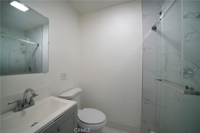 bathroom featuring baseboards, toilet, vanity, and a marble finish shower