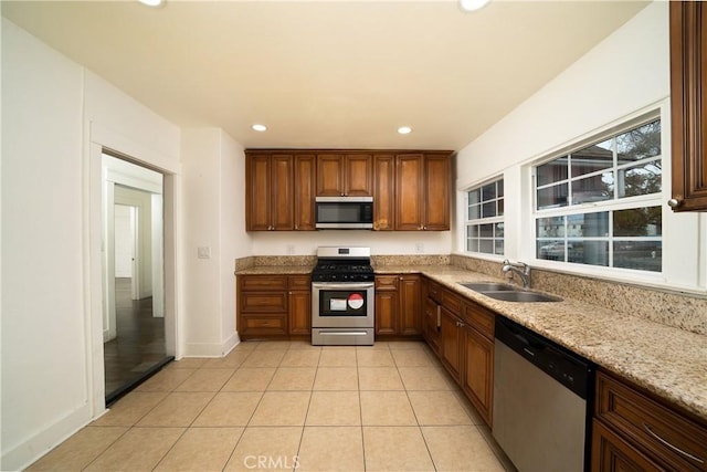 kitchen with light stone counters, light tile patterned floors, stainless steel appliances, recessed lighting, and a sink