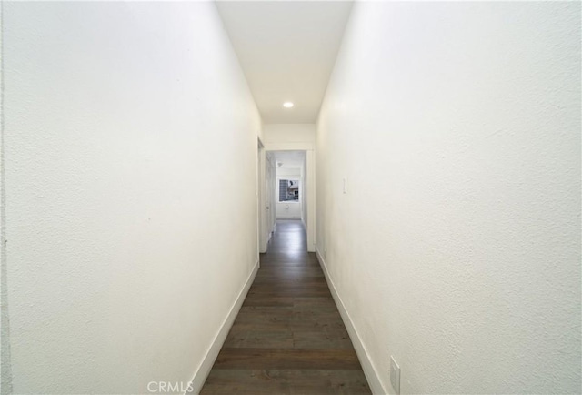 hallway featuring dark wood finished floors and baseboards