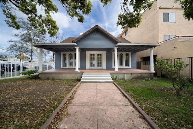 view of front of home with a porch, french doors, and fence