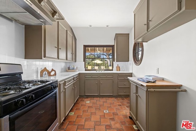 kitchen featuring premium range hood, stainless steel range with gas cooktop, sink, and decorative backsplash