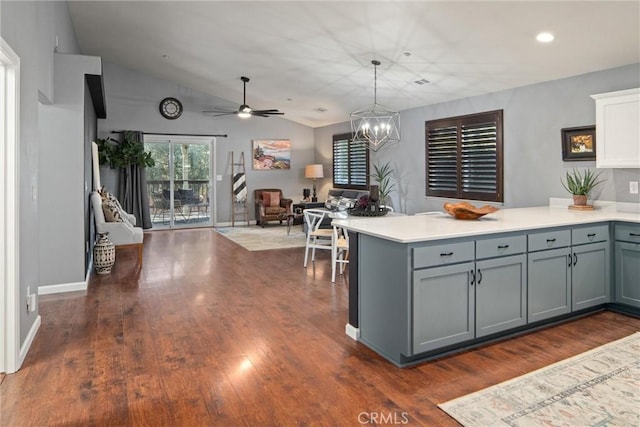 kitchen featuring decorative light fixtures, vaulted ceiling, dark hardwood / wood-style floors, gray cabinets, and ceiling fan with notable chandelier