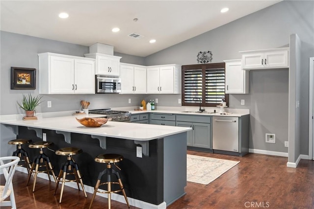 kitchen featuring gray cabinets, white cabinets, a kitchen breakfast bar, kitchen peninsula, and stainless steel appliances