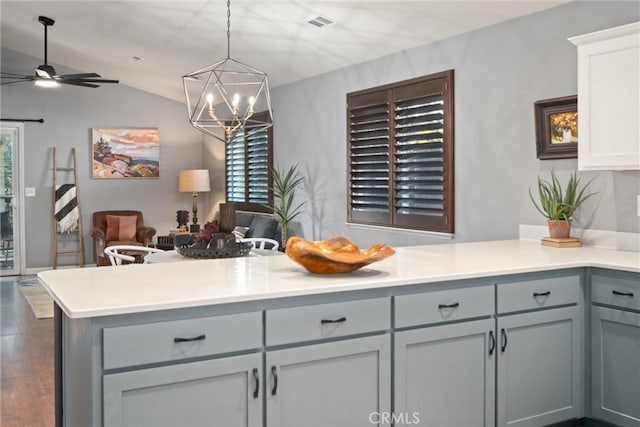 kitchen with lofted ceiling, gray cabinetry, kitchen peninsula, and decorative light fixtures