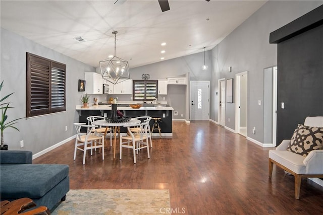 dining room with wood-type flooring, high vaulted ceiling, and an inviting chandelier