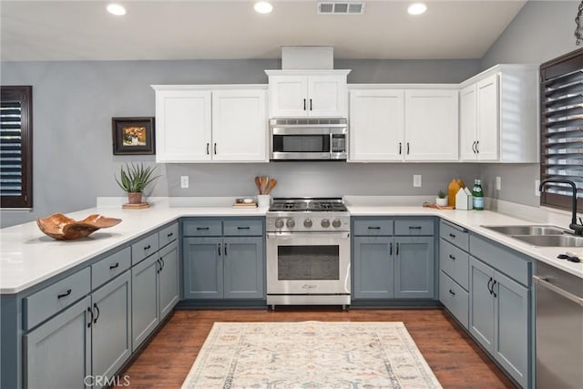 kitchen featuring appliances with stainless steel finishes, sink, gray cabinetry, white cabinets, and dark hardwood / wood-style flooring