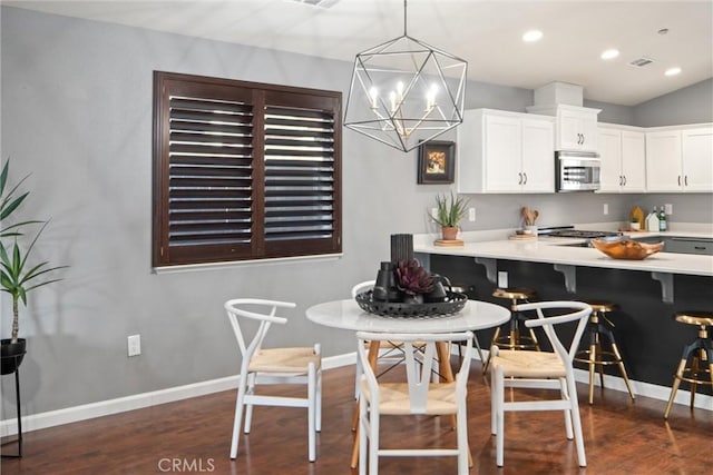 kitchen with a breakfast bar, dark hardwood / wood-style floors, white cabinetry, a chandelier, and hanging light fixtures