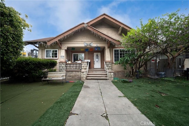 view of front facade with a porch, a front lawn, and fence