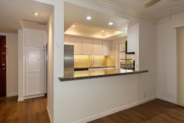 kitchen with white cabinetry, stainless steel fridge, dark stone counters, and kitchen peninsula