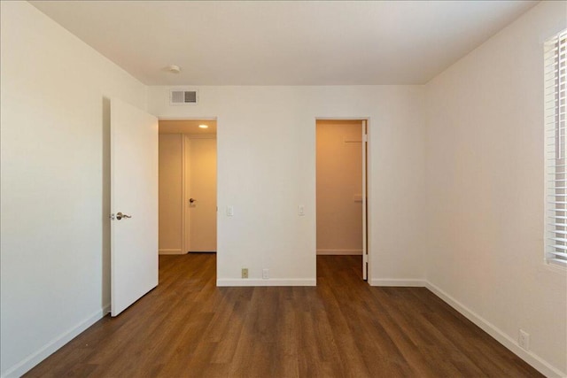 unfurnished bedroom with a spacious closet, dark hardwood / wood-style flooring, and a closet