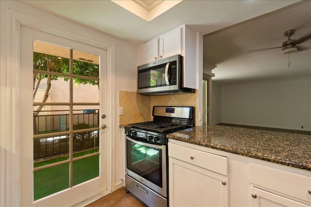 kitchen featuring dark stone countertops, ceiling fan, stainless steel appliances, decorative backsplash, and white cabinets