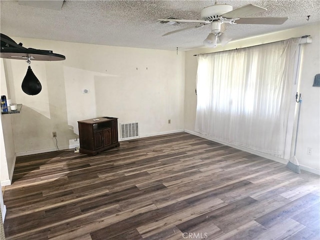 spare room featuring dark hardwood / wood-style flooring, a textured ceiling, and ceiling fan