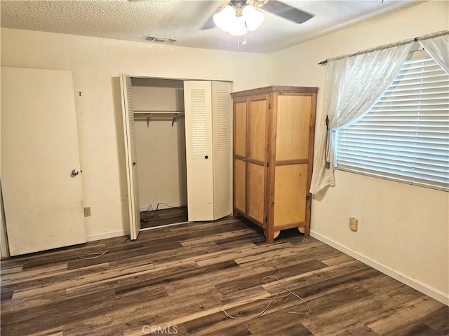 unfurnished bedroom with ceiling fan, dark hardwood / wood-style flooring, a closet, and a textured ceiling