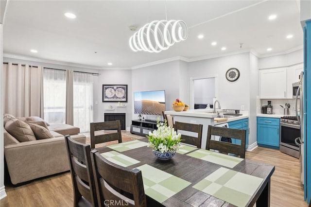 dining space with sink, ornamental molding, and light hardwood / wood-style floors