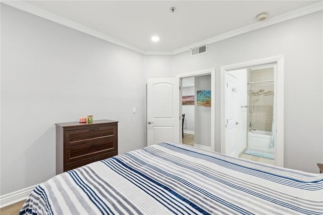 bedroom featuring ornamental molding, ensuite bathroom, and light wood-type flooring