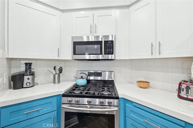 kitchen featuring white cabinets, appliances with stainless steel finishes, blue cabinets, and backsplash