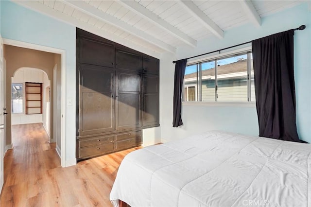 bedroom with vaulted ceiling with beams and light wood-type flooring