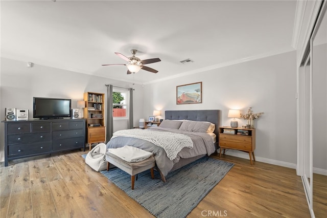 bedroom featuring crown molding, light hardwood / wood-style floors, a closet, and ceiling fan