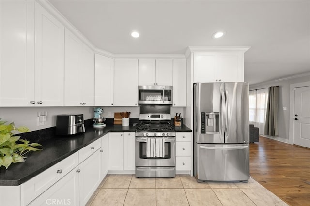 kitchen with white cabinetry, appliances with stainless steel finishes, light tile patterned flooring, and crown molding