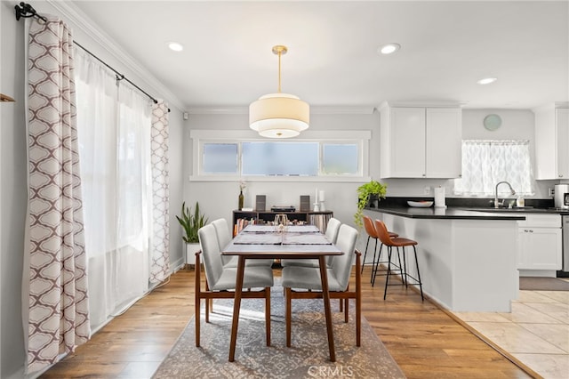 kitchen featuring light wood-type flooring, decorative light fixtures, sink, and white cabinets