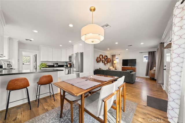 dining room featuring crown molding, sink, and light wood-type flooring