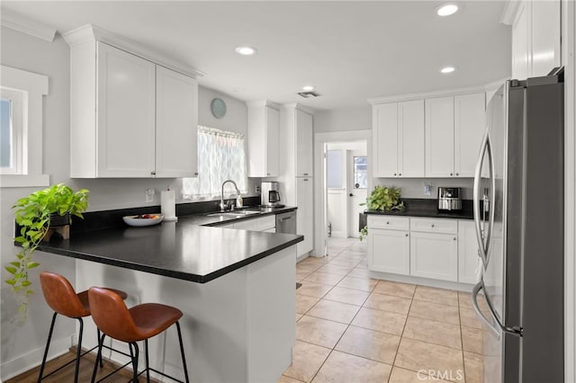 kitchen featuring white cabinetry, stainless steel fridge, kitchen peninsula, and sink