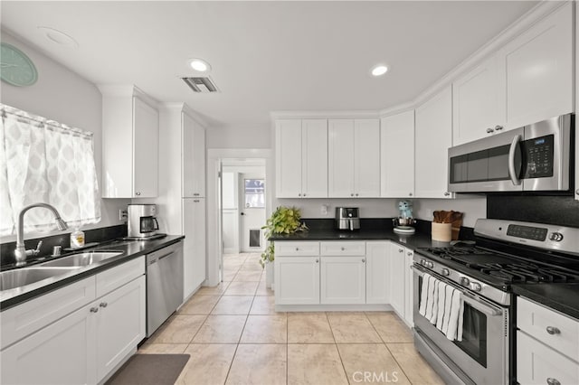 kitchen featuring white cabinetry, sink, light tile patterned floors, and stainless steel appliances