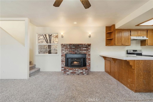 kitchen featuring a breakfast bar, light colored carpet, electric range, ceiling fan, and kitchen peninsula