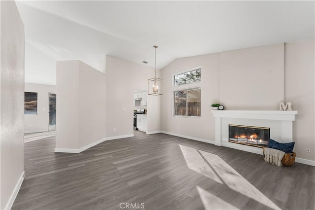 unfurnished living room with dark wood-type flooring, lofted ceiling, a tiled fireplace, and an inviting chandelier