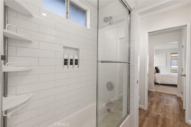 bathroom with wood-type flooring and combined bath / shower with glass door