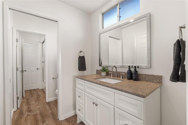 full bathroom featuring hardwood / wood-style flooring, vanity, shower / bath combination with glass door, and toilet