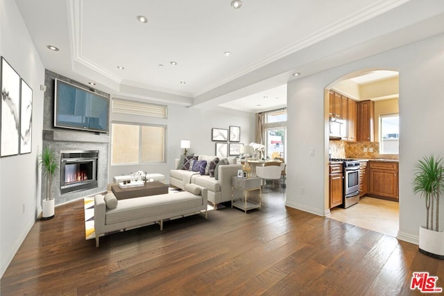 living room with hardwood / wood-style flooring, crown molding, and a large fireplace