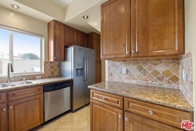 kitchen featuring sink, light tile patterned floors, backsplash, stainless steel appliances, and light stone counters