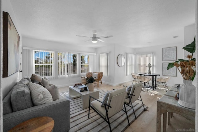 living room with ceiling fan, a wealth of natural light, and light hardwood / wood-style floors