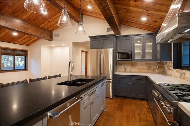 kitchen featuring appliances with stainless steel finishes, island range hood, decorative light fixtures, sink, and vaulted ceiling with beams