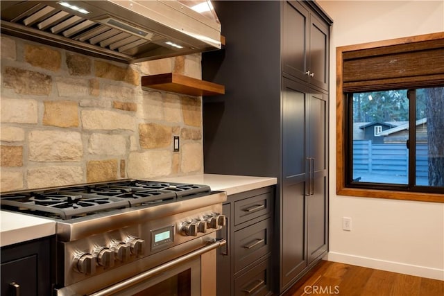 kitchen with backsplash, dark brown cabinets, dark hardwood / wood-style floors, high end stainless steel range, and wall chimney exhaust hood