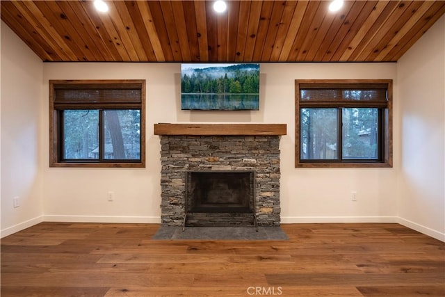 unfurnished living room featuring plenty of natural light, wood-type flooring, a fireplace, and wooden ceiling