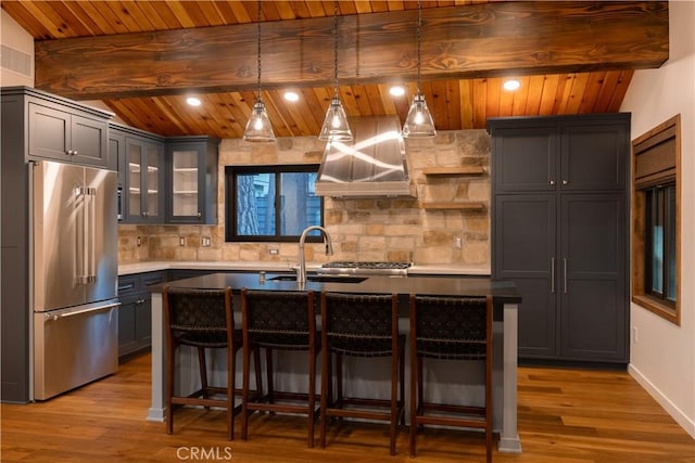 kitchen with a kitchen island with sink, hanging light fixtures, and high end refrigerator